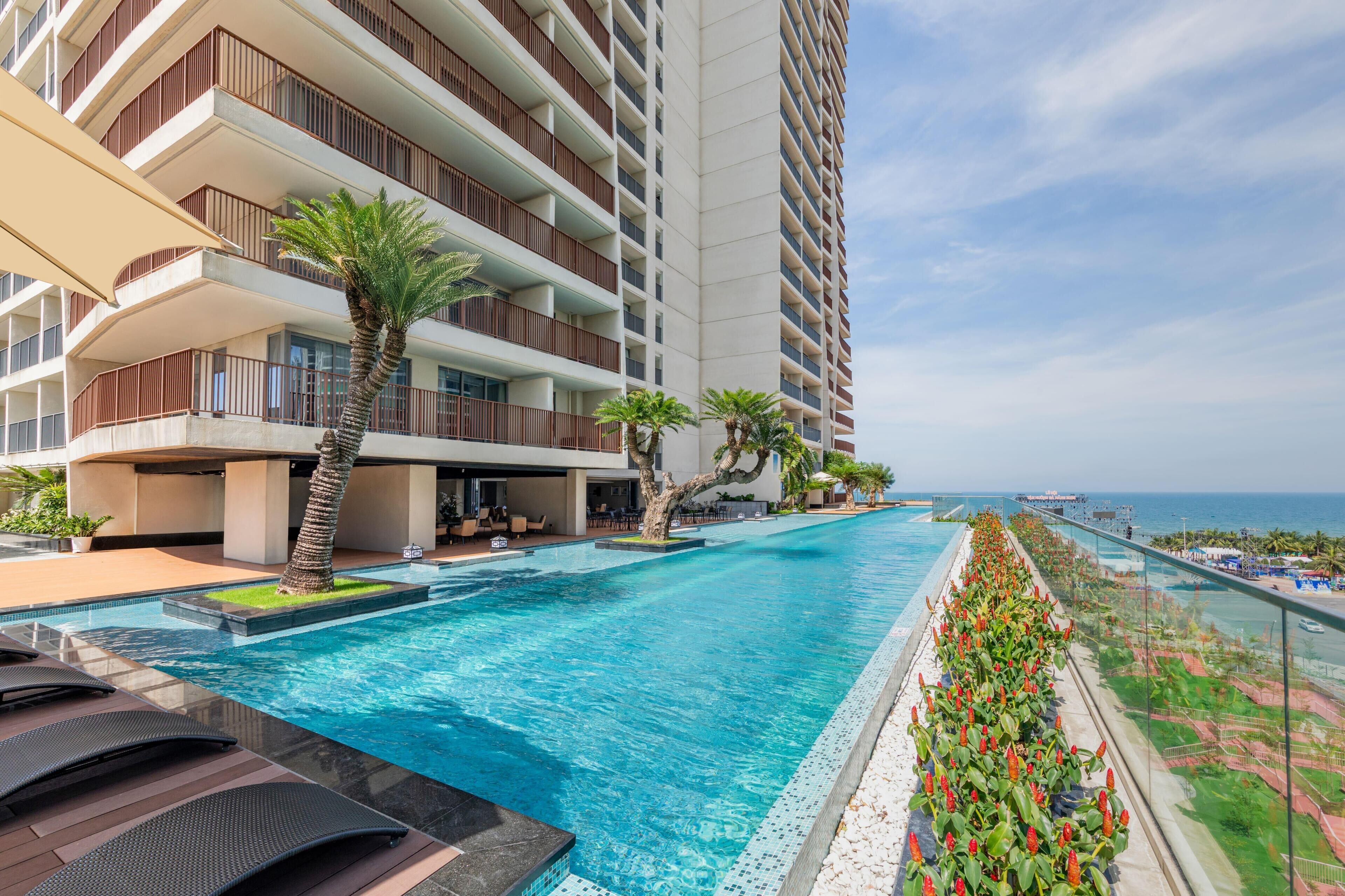 A hotel with a swimming pool, outdoor seating, and a view of the ocean.