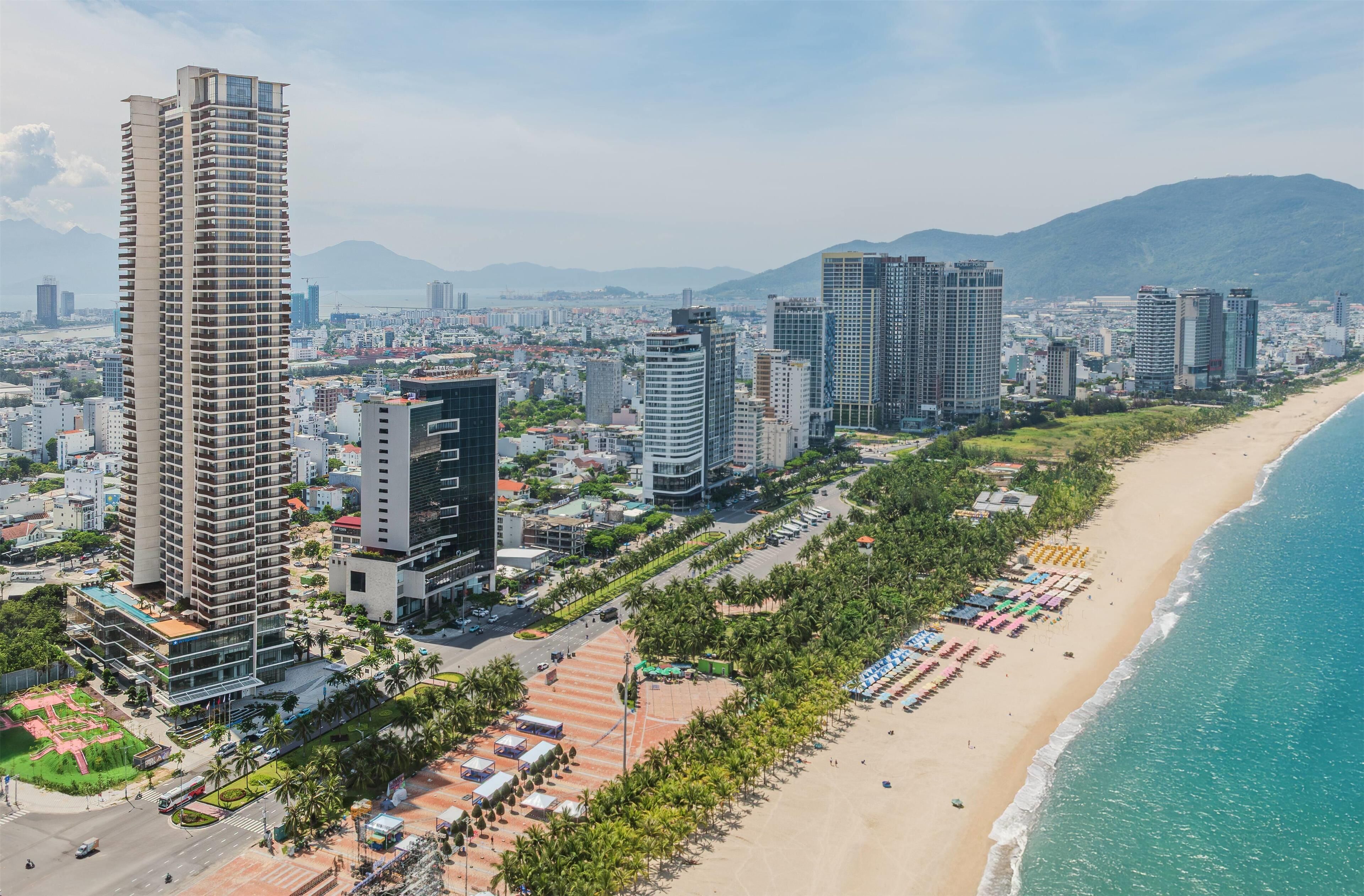 Eine Küstenstadt mit Hochhäusern, einem Strand und blauem Himmel.