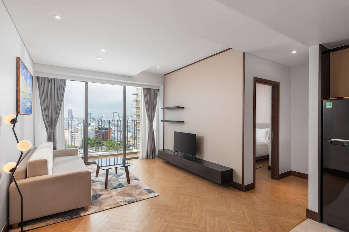 Una sala de estar moderna con un sofá, televisor y vistas a la ciudad.