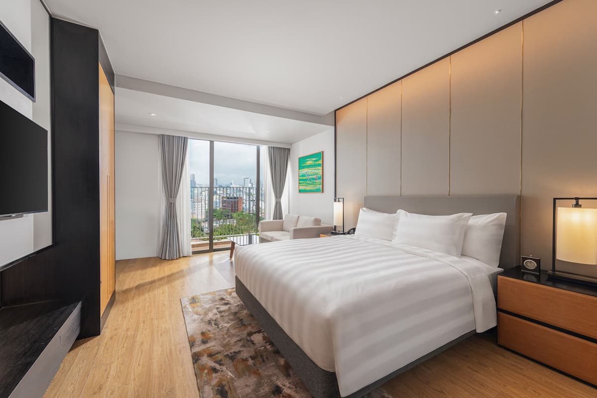 Habitación de hotel moderna con una cama grande, un escritorio, un televisor y vistas a la ciudad.