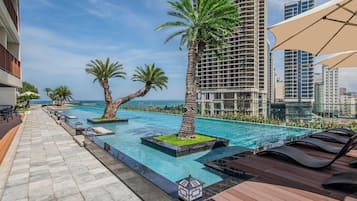Una piscina al aire libre, sombrillas, sillones reclinables de piscina