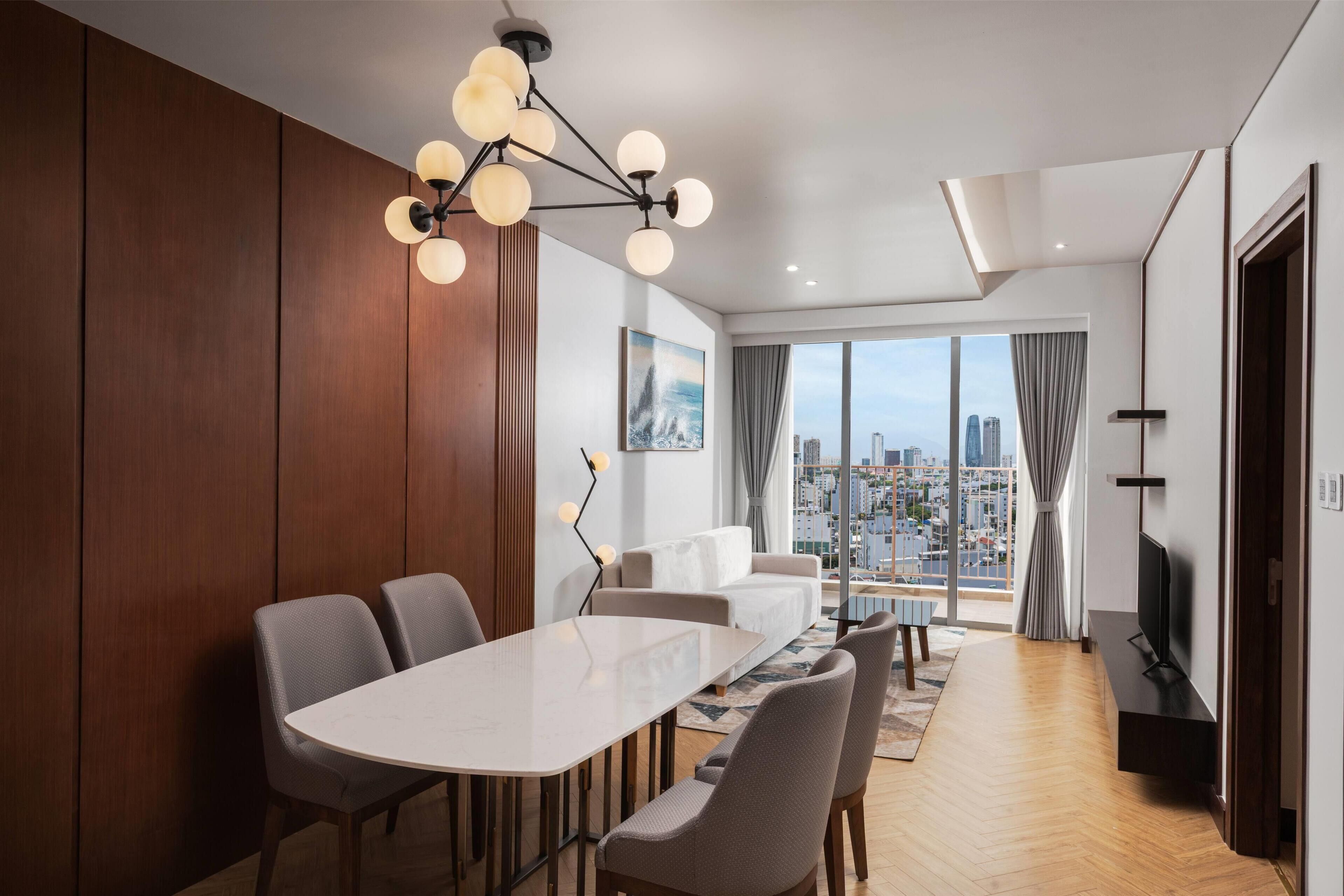 Un'elegante zona pranzo con un tavolo grande e sedie, vista sulla città attraverso ampie finestre e un moderno lampadario.