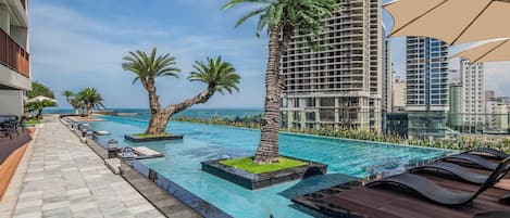 Una piscina al aire libre, sombrillas, tumbonas