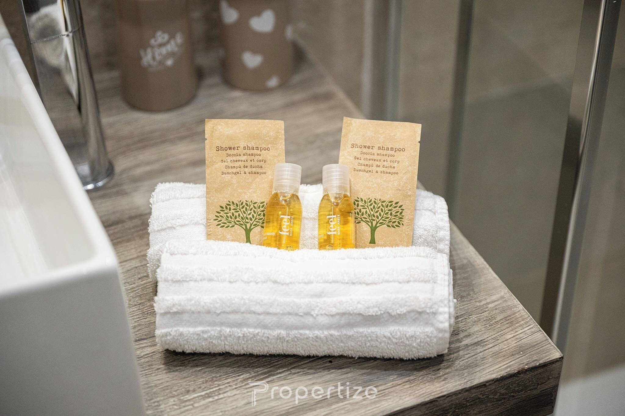 A bathroom with a white towel and two bottles of shower shampoo on a wooden surface.