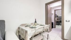 Un coin repas avec une table mise pour deux, une bouteille de vin et une chaise.