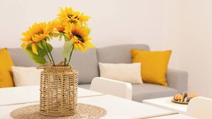 A dining table with a woven basket vase containing sunflowers, set on a placemat. - Alchimìa by Propertize (Cagliari)