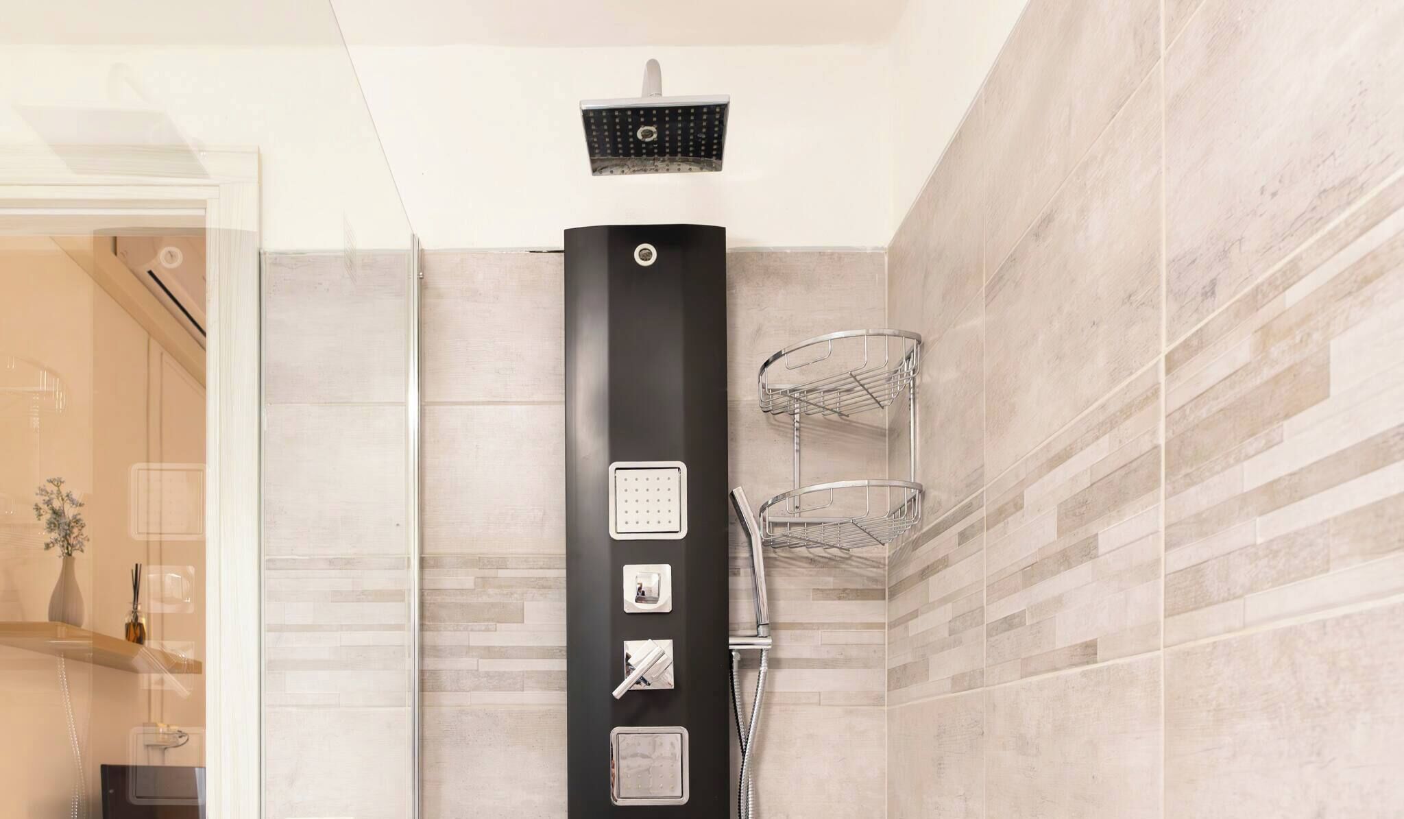 Casa de banho moderna com coluna de chuveiro preta, chuveiro manual e um chuveiro de chuva fixado na parede.