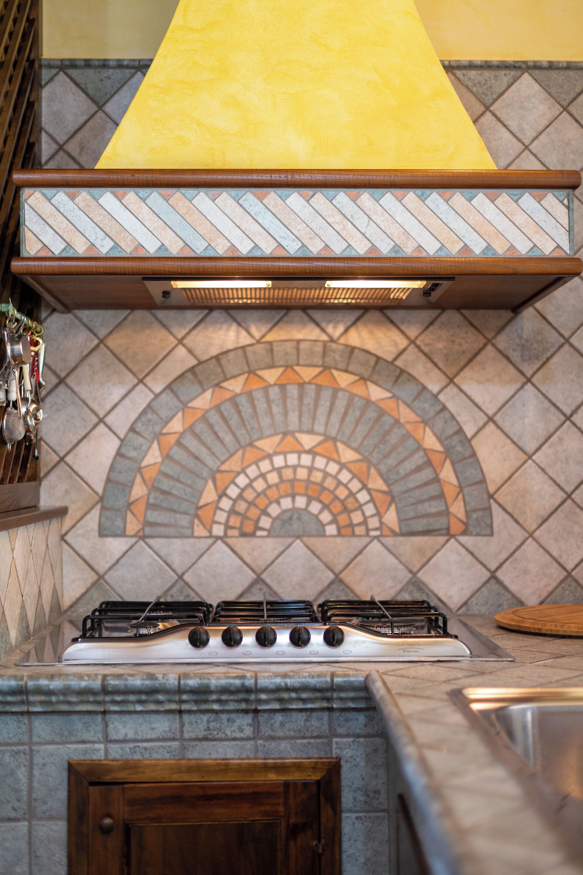 Una cocina con estufa a gas, salpicadero de azulejos y un mueble de madera.