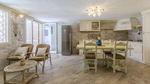 A kitchen with a dining area, featuring a chandelier, a refrigerator, and a dining table with chairs. - Villa Rachele ground floor apt, private pool (Porto Pinetto)