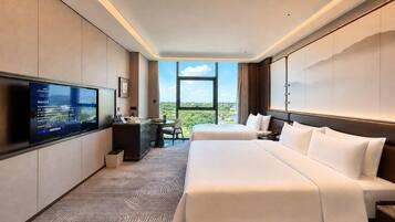 Habitación de hotel con una cama grande, un escritorio, un televisor y vistas al exterior.