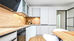 Una cocina moderna con armarios blancos, encimera de madera y horno empotrado.
