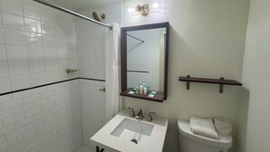 A bathroom with a white sink, a mirror, a toilet, and a shower area.