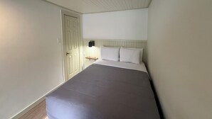 A bedroom with a bed, a nightstand, and a door.