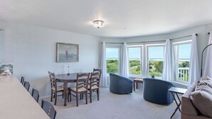 Una habitación con una mesa de comedor, sillas, un sofá y vista al océano.