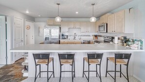 Una cocina moderna con una isla grande, electrodomésticos de acero inoxidable y armarios de madera.