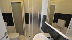 A bathroom with a toilet, a sink, and a shower enclosure. - Nice Studio With sea View Balcony in Lignano Pineta (Lignano Sabbiadoro)