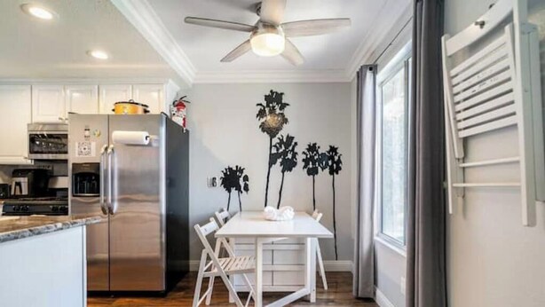 A modern kitchen with a stainless steel refrigerator, a dining table with chairs, and a ceiling fan. - Charming & Cozy Condo   • Pool-Spa & Pac-Man Arcade (Indio)