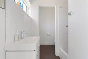 A bathroom with a white sink, a mirror, and a shower area.