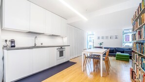 Eine moderne Küche mit weißen Schränken, einem eingebauten Ofen und einer Essecke mit Tisch und Stühlen.