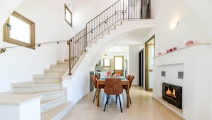 A spacious living area with a staircase, a dining table with chairs, and a fireplace. - Kymma Villa 12 in Ayia Napa (Sotira)