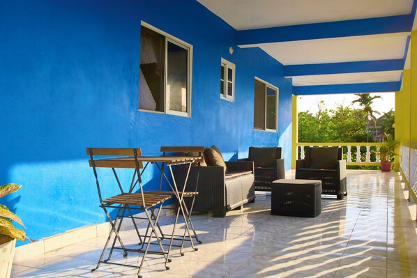 A covered patio with blue walls, wicker furniture, and a tiled floor.