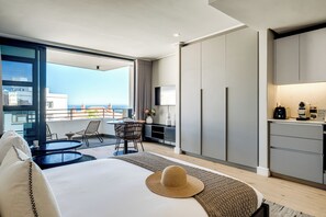 A modern hotel room with a balcony, a dining area, a kitchen, and a large bed. - Bantry Bay Retreat Ocean + Mountain Views (Cape Town)