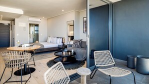 A modern hotel room with a bed, sofa, dining table, and chairs. - Bantry Bay Retreat Ocean + Mountain Views (Cape Town)