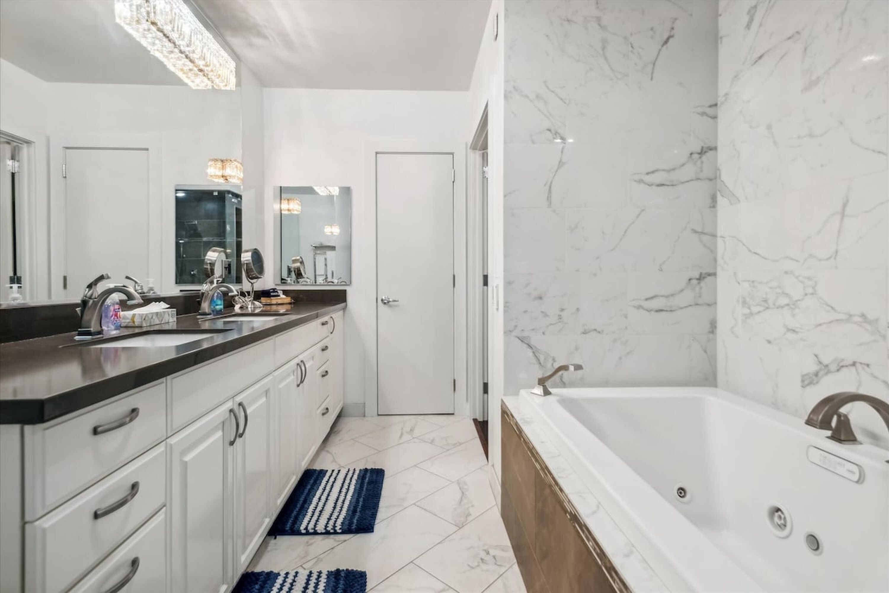 A modern bathroom with a large mirror, a bathtub, and a vanity with a sink.