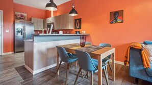A modern kitchen with a central island, blue chairs, and a dining table. - Chinook Suite - 203 in Portland (Portland)