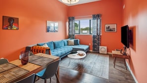 A living room with a sectional sofa, a dining table with chairs, a coffee table, a TV, and artwork on the walls. - Chinook Suite - 203 in Portland (Portland)