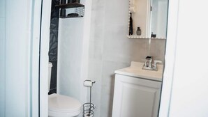 A bathroom with a white toilet, a sink with a mirror, and a shower area. - Lovely 4-BR/3BA w. 2 King Beds in Fun Cataño w. AC, WiFi, Ferry to Old San Juan (Catano)