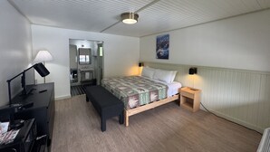 A bedroom with a bed, bedside table, lamp, and a desk with a computer and printer. - Standard King Room - NKS (Gatlinburg)