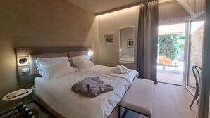 Una camera d'albergo con un letto grande, un comodino, una panca e vista sull'esterno.