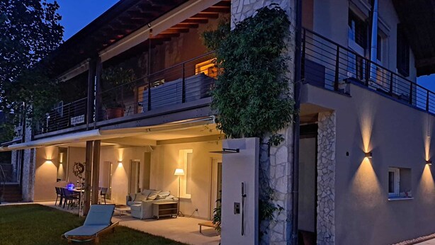Una moderna casa a due piani con patio coperto, posti a sedere all'aperto e facciata in pietra.