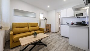 Un espacio habitable compacto con sofá, una mesita, microondas y kitchenette.