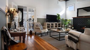 A spacious living room with a fireplace, a television, and a dining area visible through an open door.