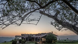 A large, multi-story building with a covered patio area, surrounded by well-maintained lawns and a tree. - Infinite autumn in the Asturian coast with family (Marianes)