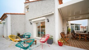Une terrasse extérieure couverte, aménagée avec différents types de sièges, notamment des chaises et une table.