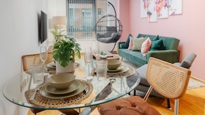 A modern living room with a glass dining table, a hanging chair, and a green sofa.