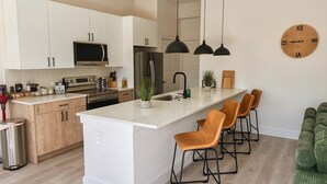 Une cuisine moderne avec des meubles blancs, un îlot central et des luminaires suspendus.