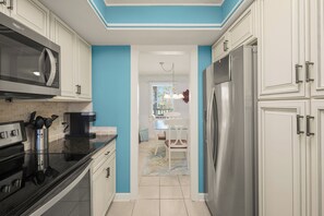 Una cocina moderna con armarios blancos, electrodomésticos de acero inoxidable y una pared de acento azul.