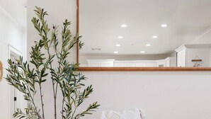 A modern living room with a wooden floor, a green sofa, a white potted plant, and a mirror on the wall. - Escondido Oasis | Sleeps 10 + Hot Tub! (Escondido)