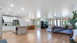 A spacious living area with a wooden floor, a dining table, and a sofa. - Escondido Oasis | Sleeps 10 + Hot Tub! (Escondido)