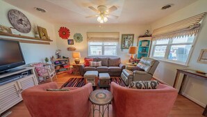 A living room with a sofa, armchairs, a television, and a ceiling fan. - Counting Pelicans + Ocean View + Pelican Hunt (Kill Devil Hills)