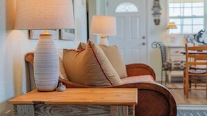 A cozy living room with a wooden coffee table, a patterned lamp, and a sofa with cushions. - Counting Pelicans + Ocean View + Pelican Hunt (Kill Devil Hills)