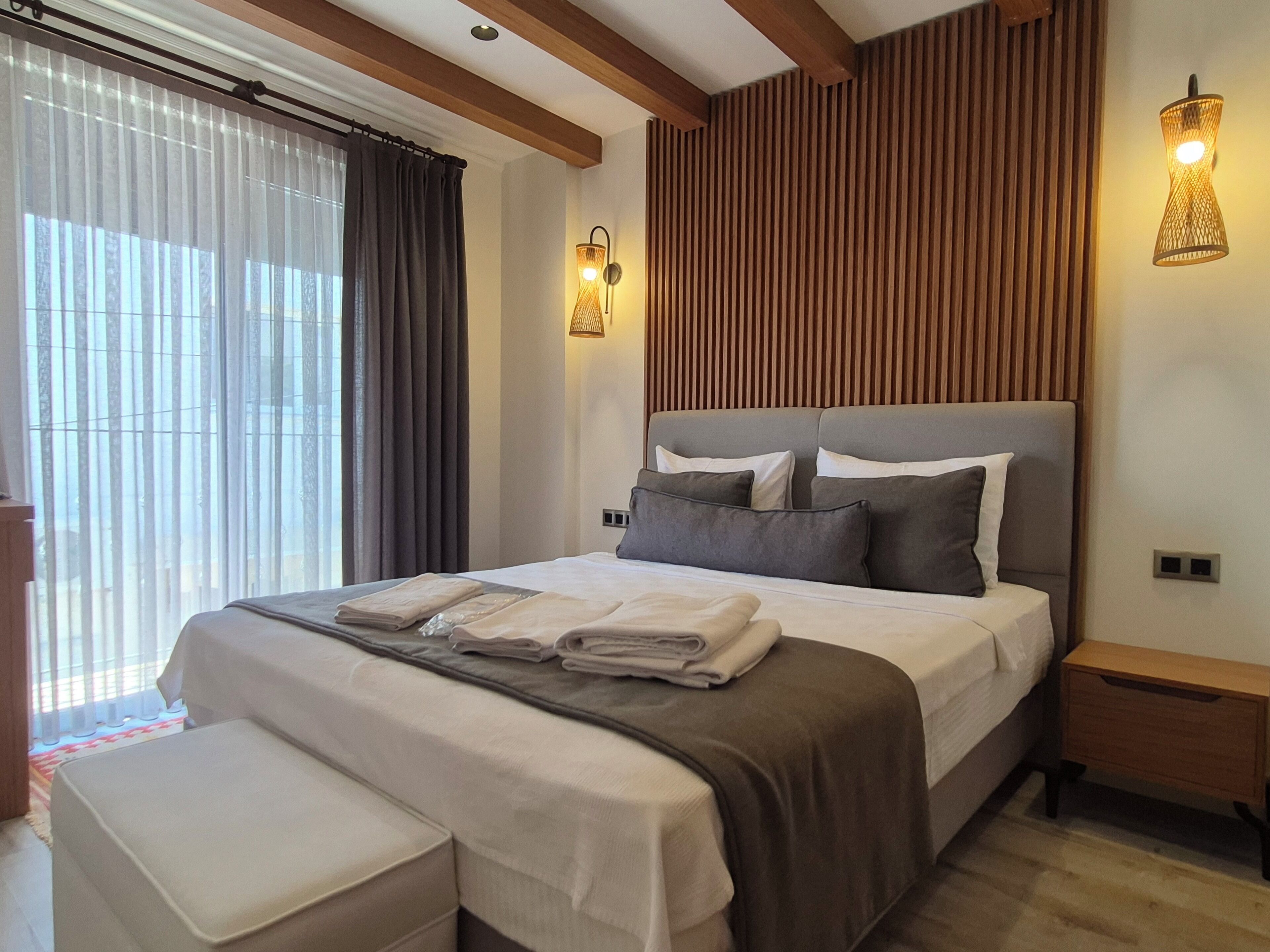 A modern bedroom with a large bed, bedside tables, and a window with curtains.