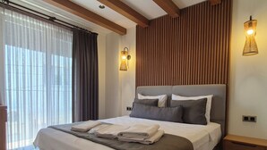 A modern bedroom with a large bed, bedside tables, and a window with curtains. - EDRA HOUSE  (Cesme)