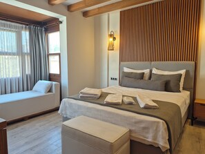 Un dormitorio bien iluminado con cama, mesitas de noche, ventana con cortinas y techo de madera.