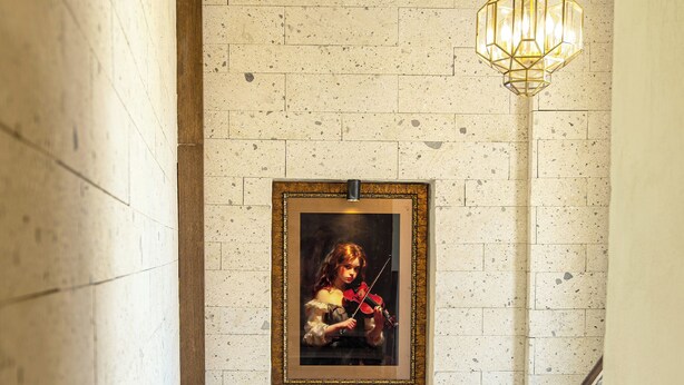 A staircase with a framed painting of a violinist, a textured wall, and a metal railing. - EDRA HOUSE  (Cesme)