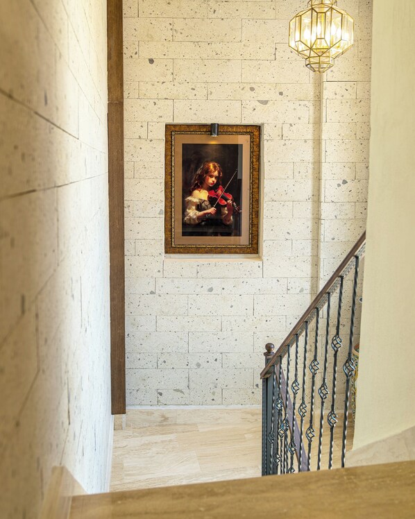 A staircase with a framed painting of a violinist, a textured wall, and a metal railing. - EDRA HOUSE  (Cesme)